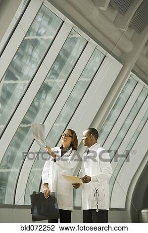 Stock Image - African doctors reviewing x-rays by window. Fotosearch