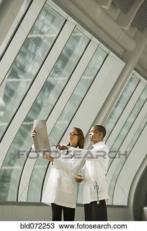 Stock Image - African doctors reviewing x-rays by window. Fotosearch