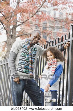 Stock Image - African father and daughter near fence. Fotosearch