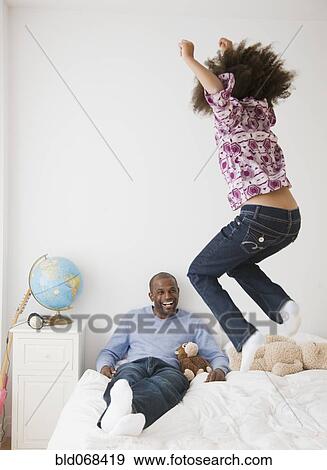 Stock Photo - African father and daughter playing on bed. Fotosearch