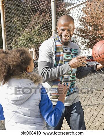 Stock Image - African father and daughter playing basketball. Fotosearch
