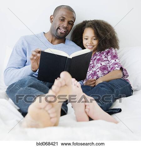 African father reading to daughter on bed View Large Photo Image Stock Image - African father reading to daughter on bed. Fotosearch