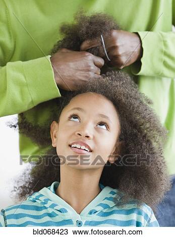 Stock Image - African father styling daughter's hair. Fotosearch