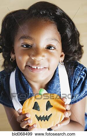 African girl holding Halloween cookie View Large Photo Image Stock Photo - African girl holding Halloween cookie. Fotosearch