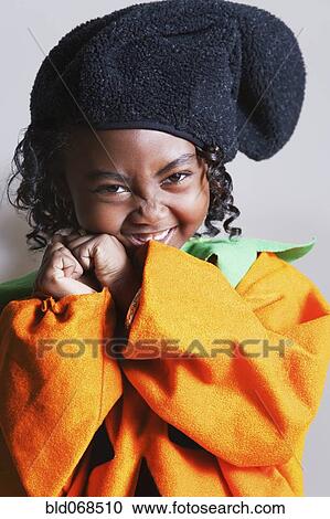 Stock Image - African girl wearing pumpkin costume. Fotosearch
