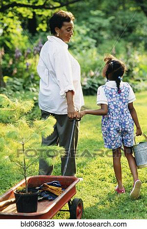 Stock Image - African grandmother and granddaughter gardening. Fotosearch