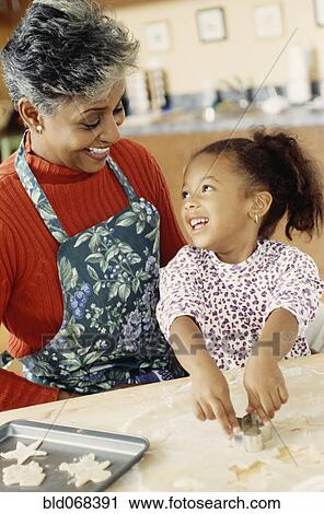 Stock Image - African grandmother and granddaughter making cookies. Fotosearch