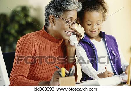 Stock Image - African grandmother and granddaughter using telephone. Fotosearch