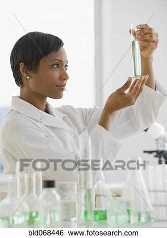 Stock Photograph - African scientist looking at vial of liquid. Fotosearch