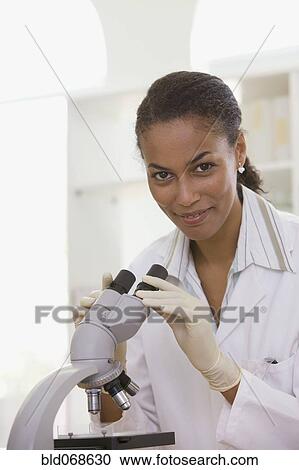 Stock Image - African scientist performing analysis in laboratory with microscope. Fotosearch