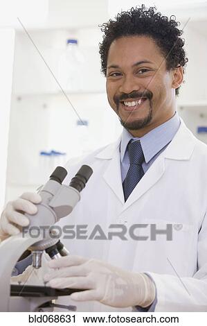 Stock Image - African scientist performing analysis in laboratory with microscope. Fotosearch