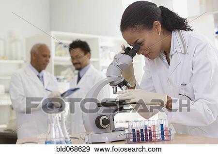 Stock Photo - African scientist performing analysis in laboratory with microscope. Fotosearch