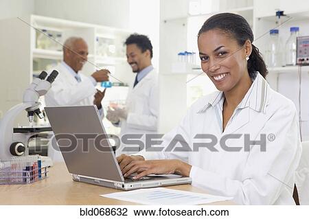 Stock Image - African scientist typing on laptop in laboratory. Fotosearch