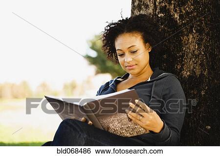African woman holding book under tree View Large Photo Image Stock Photograph - African woman holding book under tree. Fotosearch