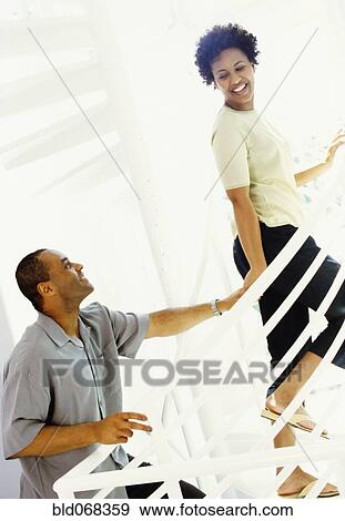 Stock Photo - African woman leading husband upstairs. Fotosearch