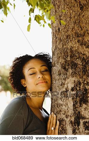 Stock Photo - African woman leaning against tree with eyes closed. Fotosearch