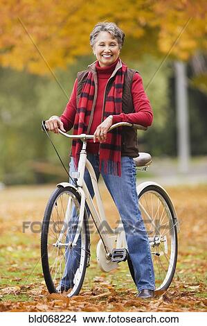 African woman standing with bicycle in park in autumn View Large Photo Image Picture - African woman standing with bicycle in park in autumn. Fotosearch