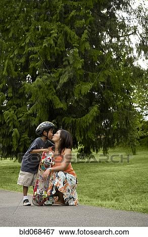 Stock Photo - Asian boy with skateboard kissing mother. Fotosearch