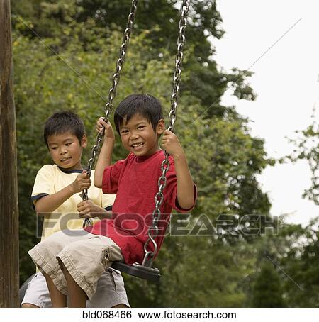 Stock Photograph - Asian boys swinging on playground. Fotosearch