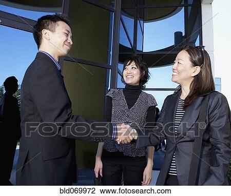 Stock Image - Asian businesspeople shaking hands. Fotosearch