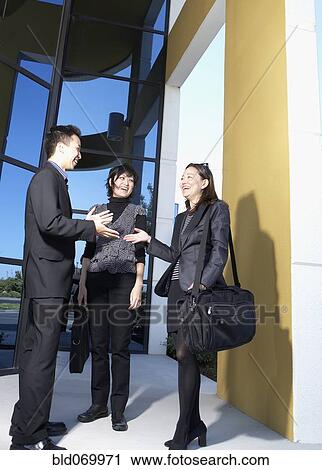 Stock Image - Asian businesspeople talking outdoors. Fotosearch