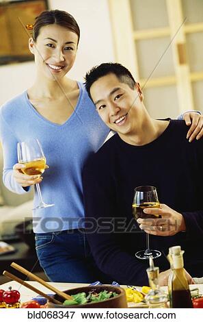 Stock Photo - Asian couple drinking wine in kitchen. Fotosearch