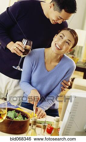Stock Photograph - Asian couple hugging in kitchen. Fotosearch