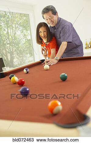 Stock Image - Asian couple playing pool. Fotosearch