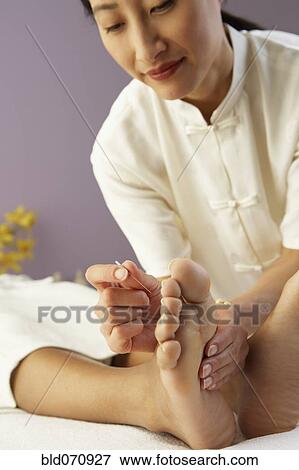 Stock Photo - Asian female doctor performing Acupuncture treatment. Fotosearch