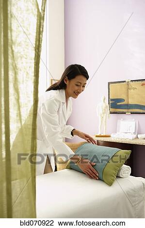 Stock Image - Asian female doctor preparing treatment table. Fotosearch