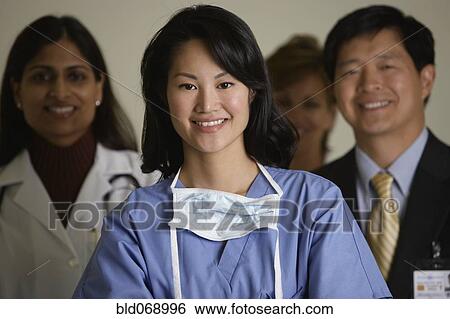 Stock Photograph - Asian female doctor smiling with coworkers in background. Fotosearch