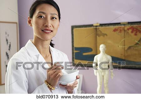 Stock Image - Asian female doctor using mortal and pestle. Fotosearch
