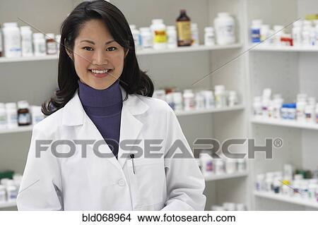 Picture - Asian female pharmacist smiling in pharmacy. Fotosearch