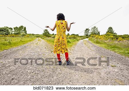 Stock Image - Asian woman shrugging at split in road. Fotosearch