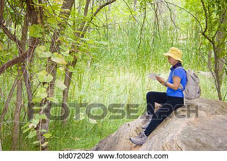 Stock Photo - Asian woman sitting on rock. Fotosearch