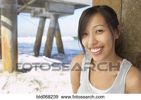 Asian woman smiling near pier at beach View Large Photo Image Stock Photo - Asian woman smiling near pier at beach. Fotosearch