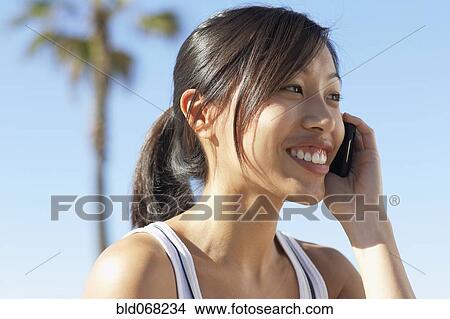 Picture - Asian woman using cell phone. Fotosearch