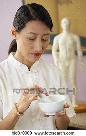 Stock Photo - Asian woman using mortar and pestle. Fotosearch