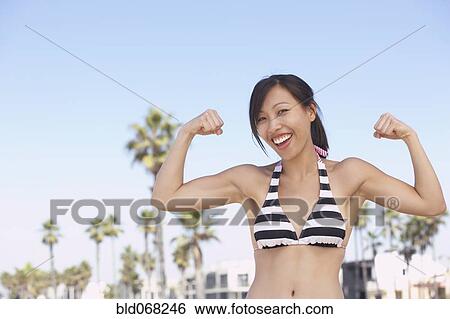 Asian woman wearing bikini showing muscles View Large Photo Image Stock Photograph - Asian woman wearing bikini showing muscles. Fotosearch