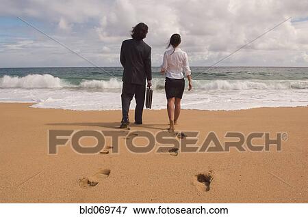 Stock Photo - Businessman and businesswoman walking towards ocean. Fotosearch