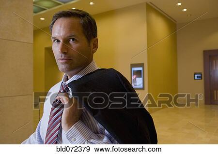 Businessman holding suit jacket over shoulder View Large Photo Image Stock Photo - Businessman holding suit jacket over shoulder. Fotosearch