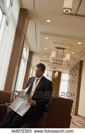 Businessman reading newspaper in lobby View Large Photo Image Stock Image - Businessman reading newspaper in lobby. Fotosearch