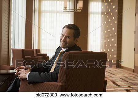 Stock Image - Businessman smiling in lobby. Fotosearch