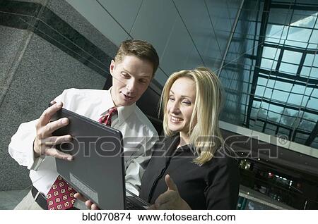 Businesspeople looking at laptop View Large Photo Image Picture - Businesspeople looking at laptop. Fotosearch