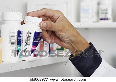 Stock Photo - Close up of female pharmacist taking medication off shelf. Fotosearch