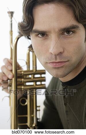 Stock Image - Close up of Hispanic man holding trumpet. Fotosearch