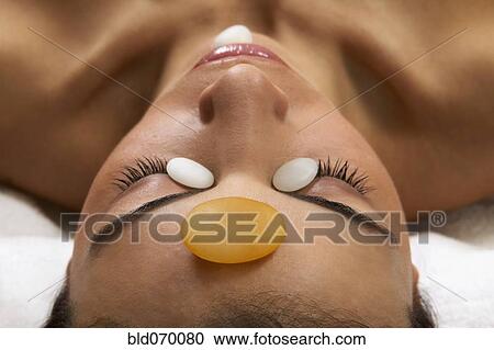 Stock Image - Close up of Hispanic woman receiving stone spa treatment. Fotosearch