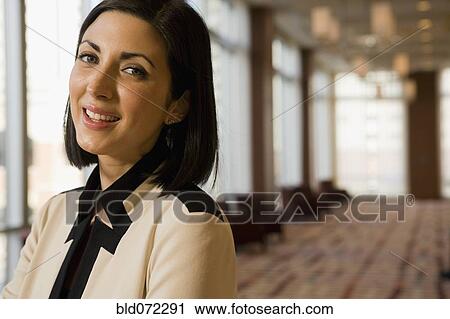 Stock Image - Close up of mixed race businesswoman smiling in corridor. Fotosearch