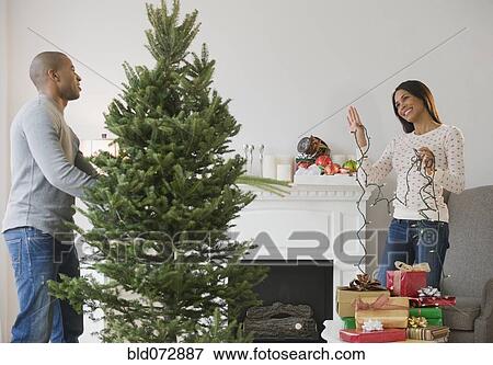Stock Photo - Couple decorating Christmas tree. Fotosearch