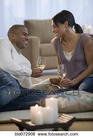 Stock Photo - Couple drinking white wine on living room floor. Fotosearch